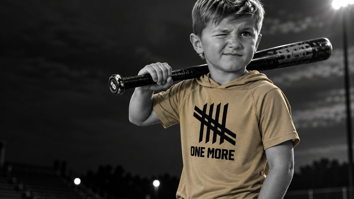 Young T-ball player wearing a helmet with a bat on his shoulder