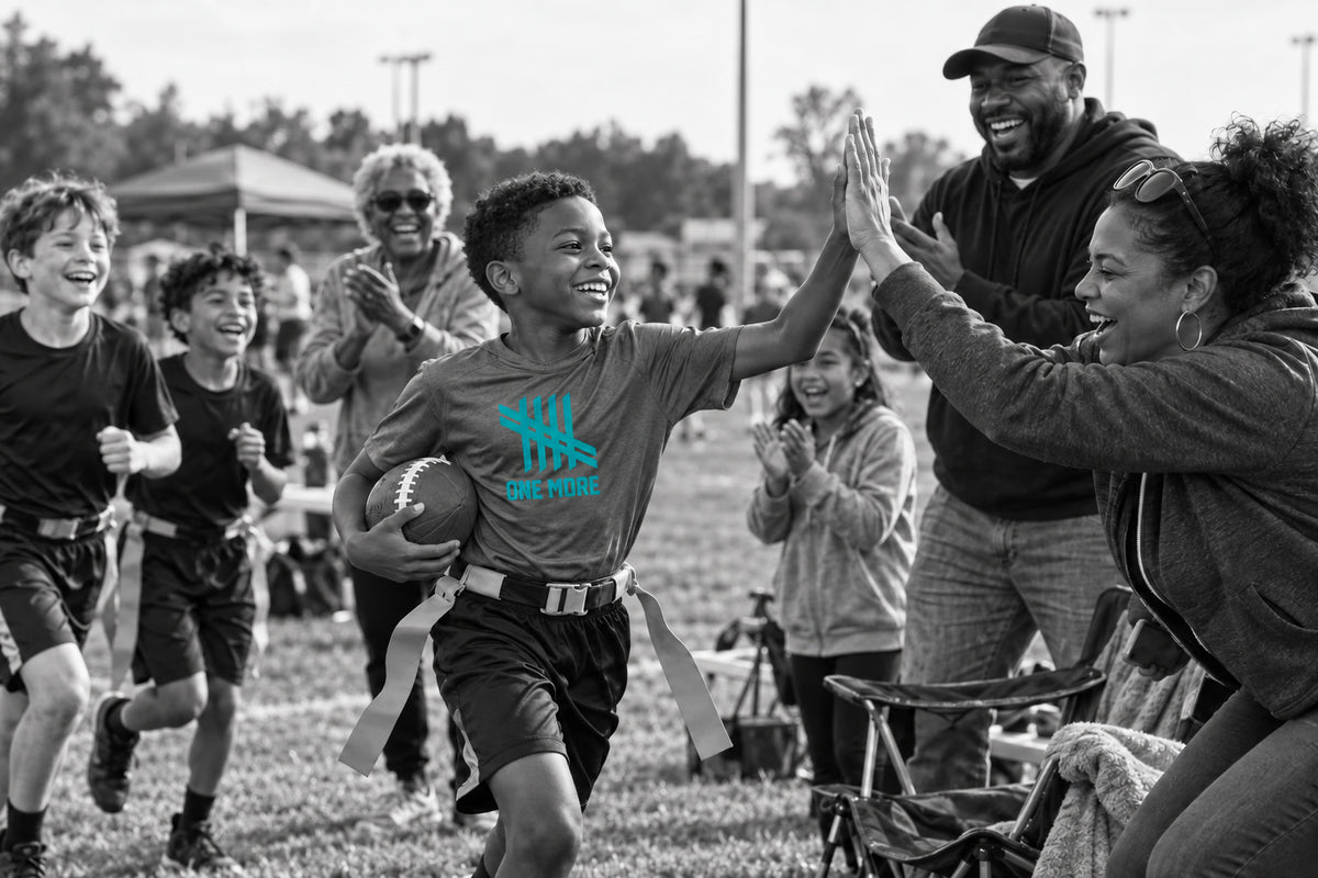 A young flag football player celebrating with his family and community on the sideline